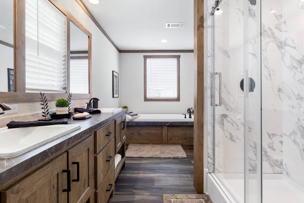 Primary bath with long vanity, glass shower, and soaking tub in the Isabella Elite