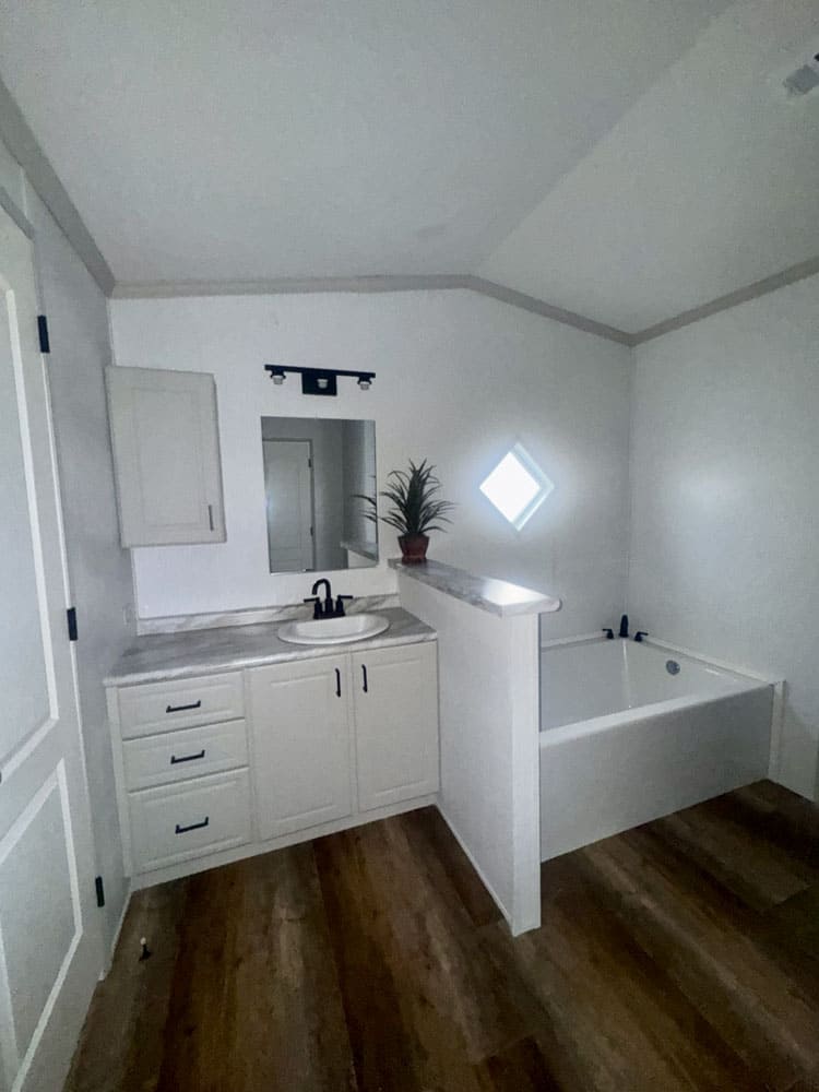 Primary bathroom vanity and soaking tub in the H-1880-32E mobile home