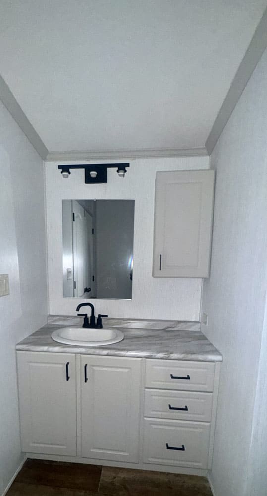 White bathroom vanity in the Legacy Housing H-1880-32E manufactured home