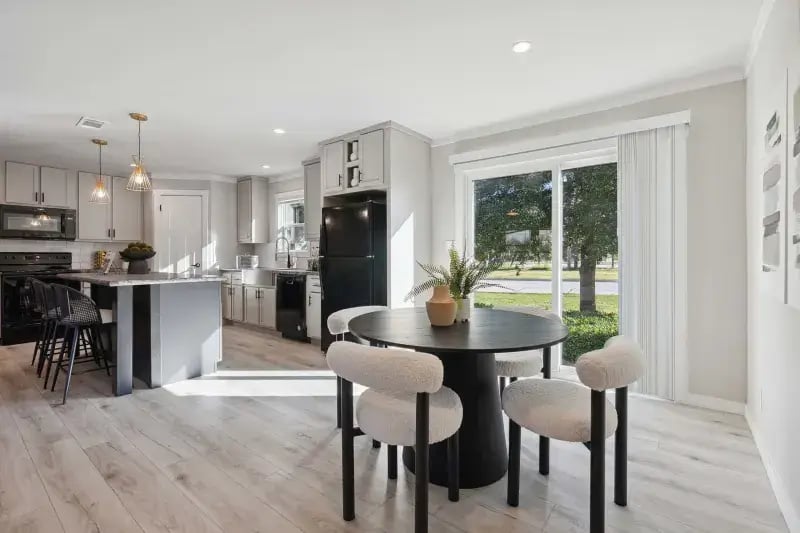 Sunlit dining area connected to the island kitchen in The Carol Champion Homes model