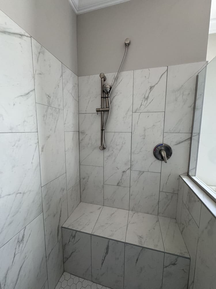 Walk-in tile shower with built-in bench and handheld sprayer in The Lilly II