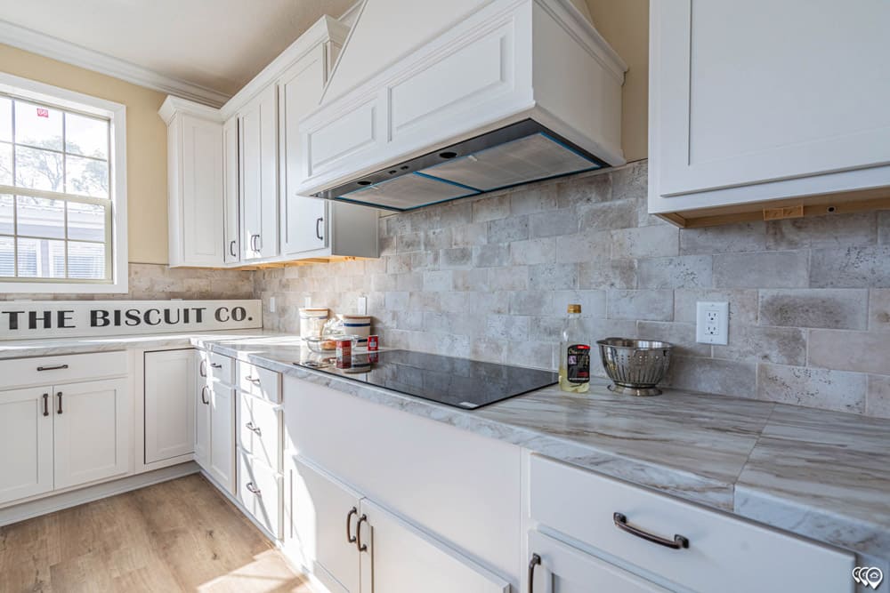 Modern cooktop with tile backsplash and custom range hood
