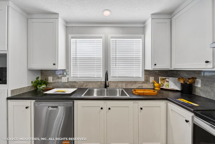 Kitchen sink, dishwasher and white cabinets in The Vantage manufactured home