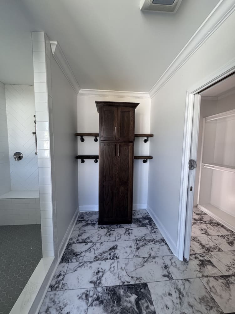Primary bathroom storage cabinet beside the tiled shower in The Shoreline
