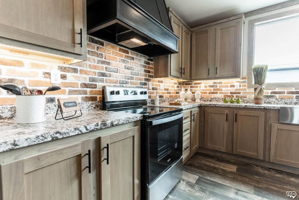 Timber Creek Housing kitchen with wood cabinets and brick backsplash