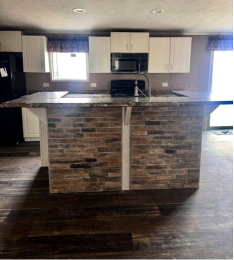 Stone-accent kitchen island in The Leslie home for sale in Conroe