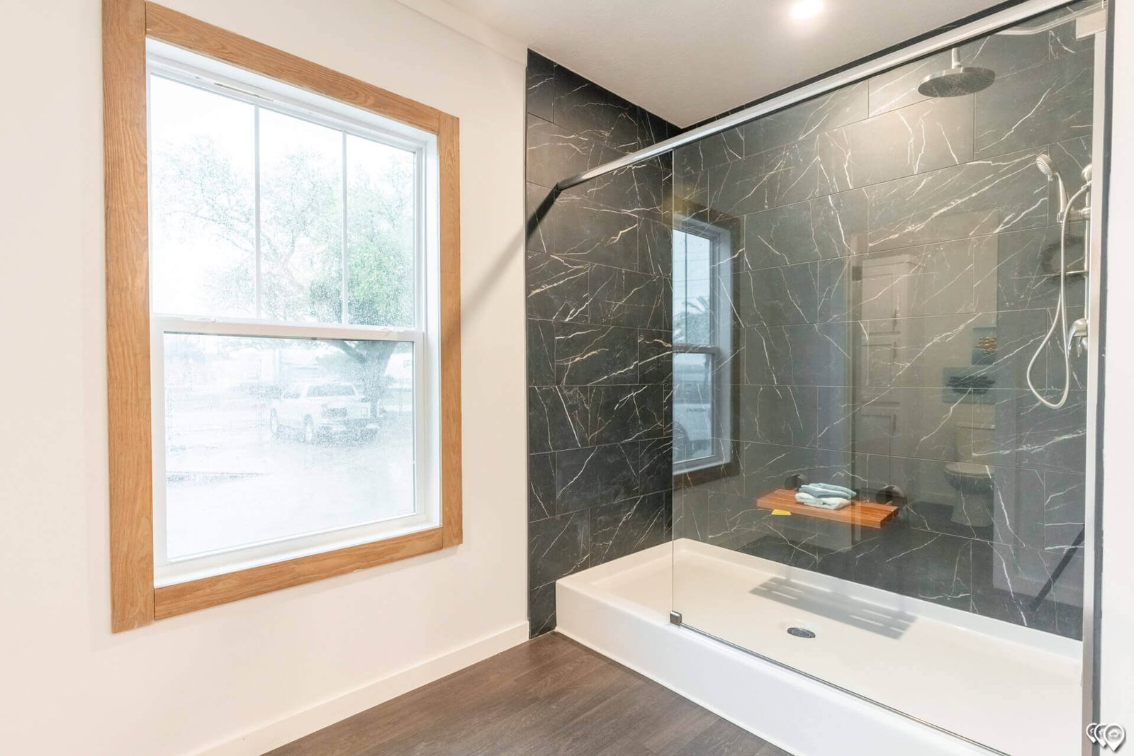 Primary bathroom glass shower with dark marble-look tile in The Trinity CS-3242