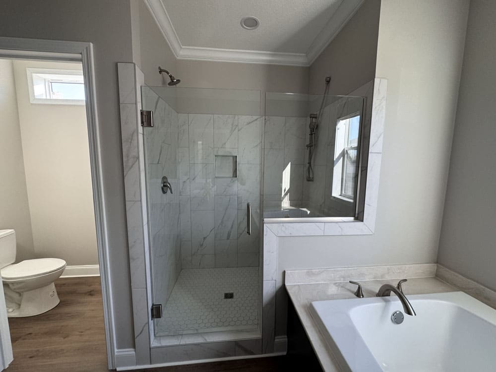 Glass-enclosed tile shower beside the soaking tub in The Lilly II