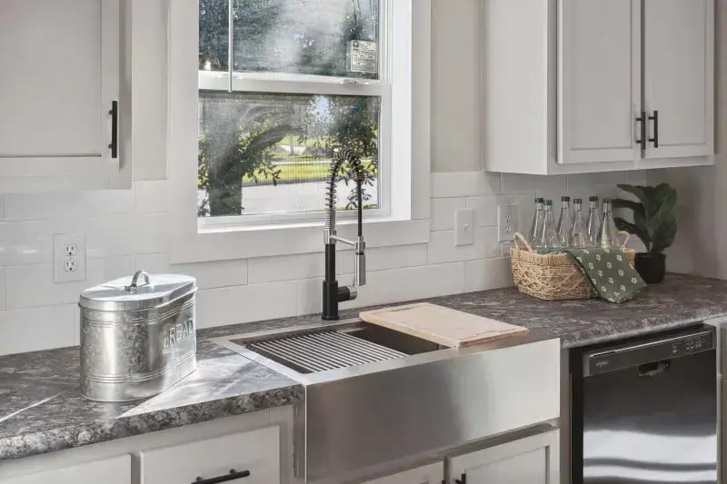 Farmhouse kitchen sink, tile backsplash and dishwasher in The Carol by Champion Homes