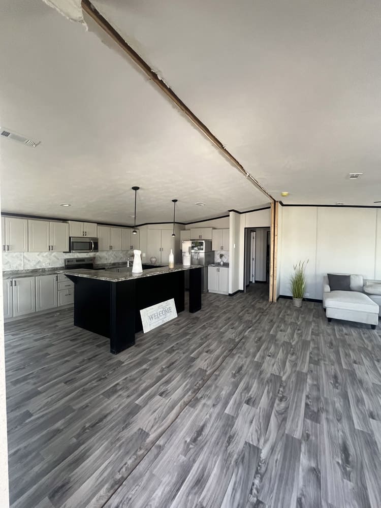 Kitchen with black island and light cabinets in the Legacy FG-H-326432AD 3-bedroom manufactured home