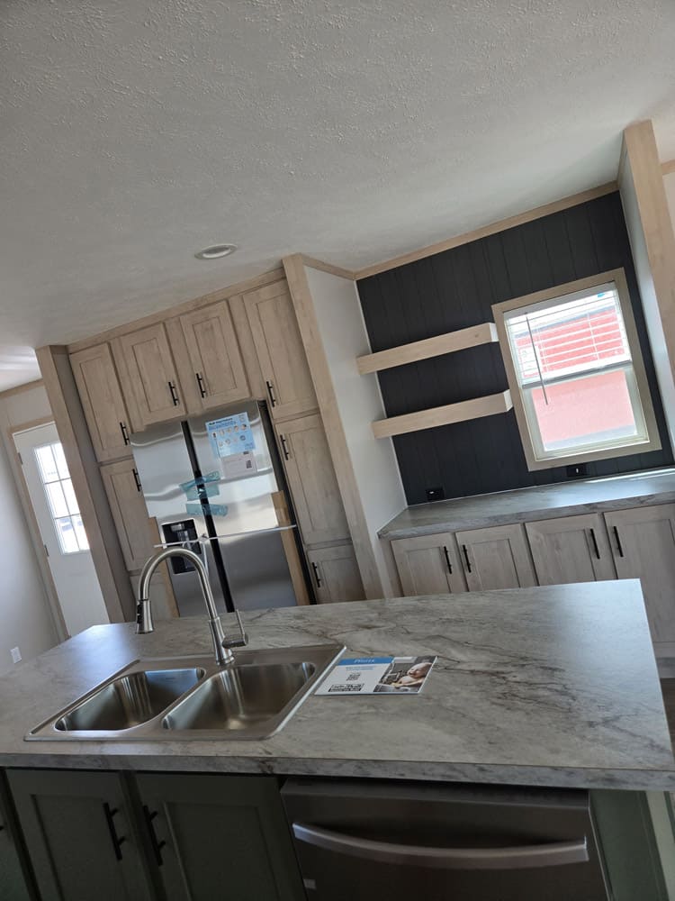 Island sink and stainless dishwasher facing the refrigerator in the Clayton Epic Hudson 3-bedroom manufactured home