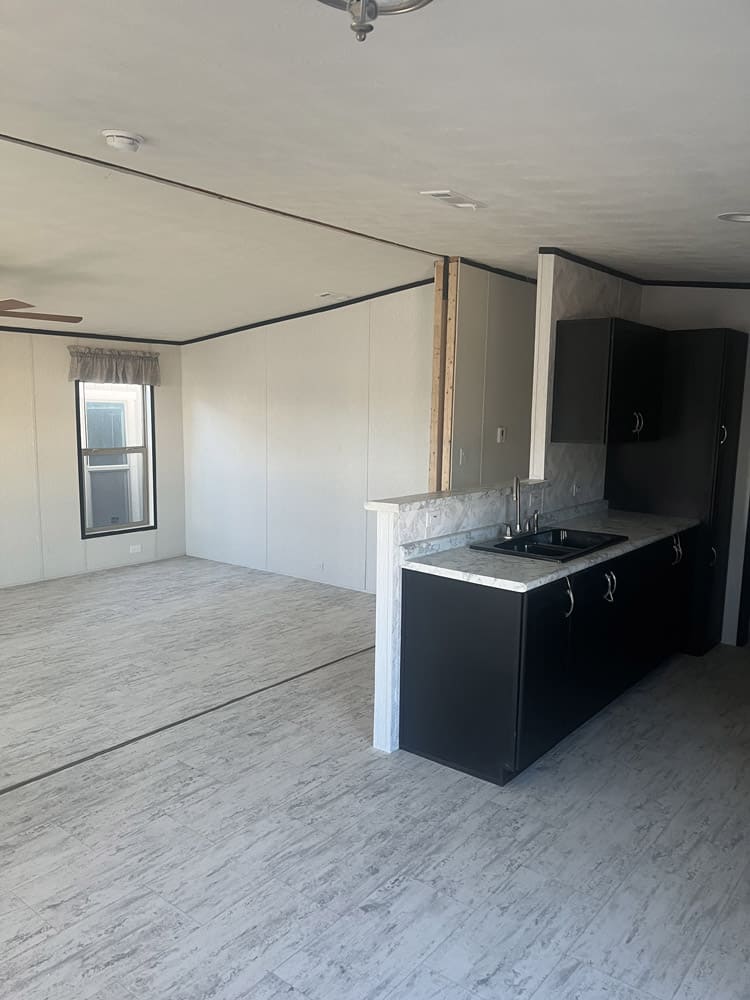 Kitchen breakfast bar opening to the living area in the Legacy S-2856-32 FLP 28x56 home in El Paso
