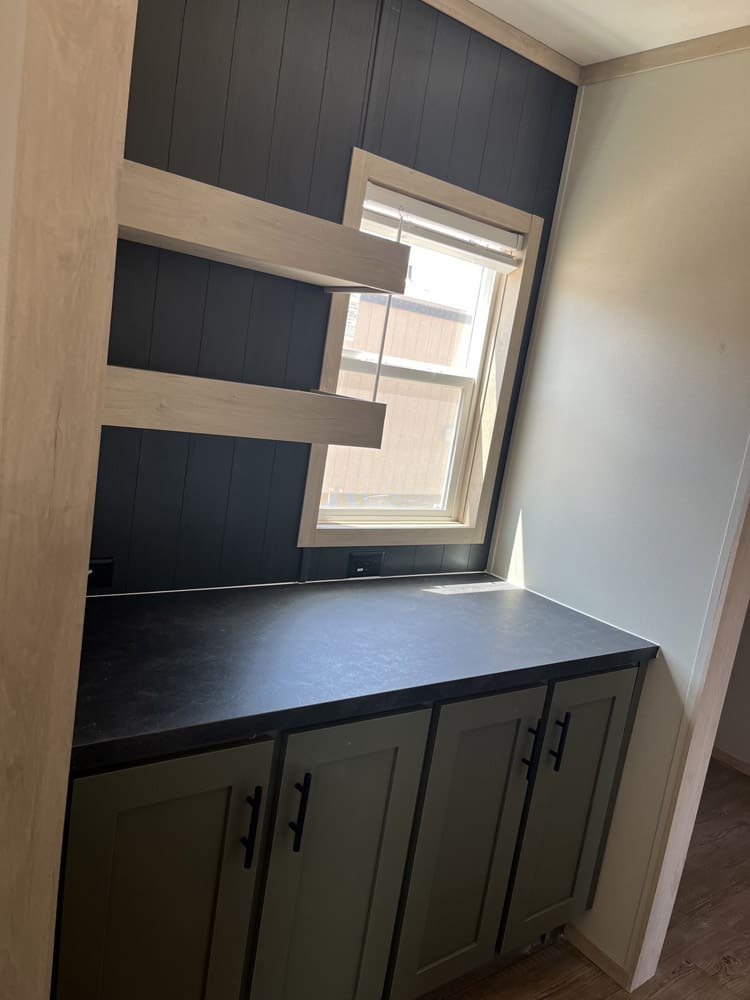Built-in sideboard and open shelves on a dark accent wall in the Clayton Epic Mariner 16x80 home in El Paso