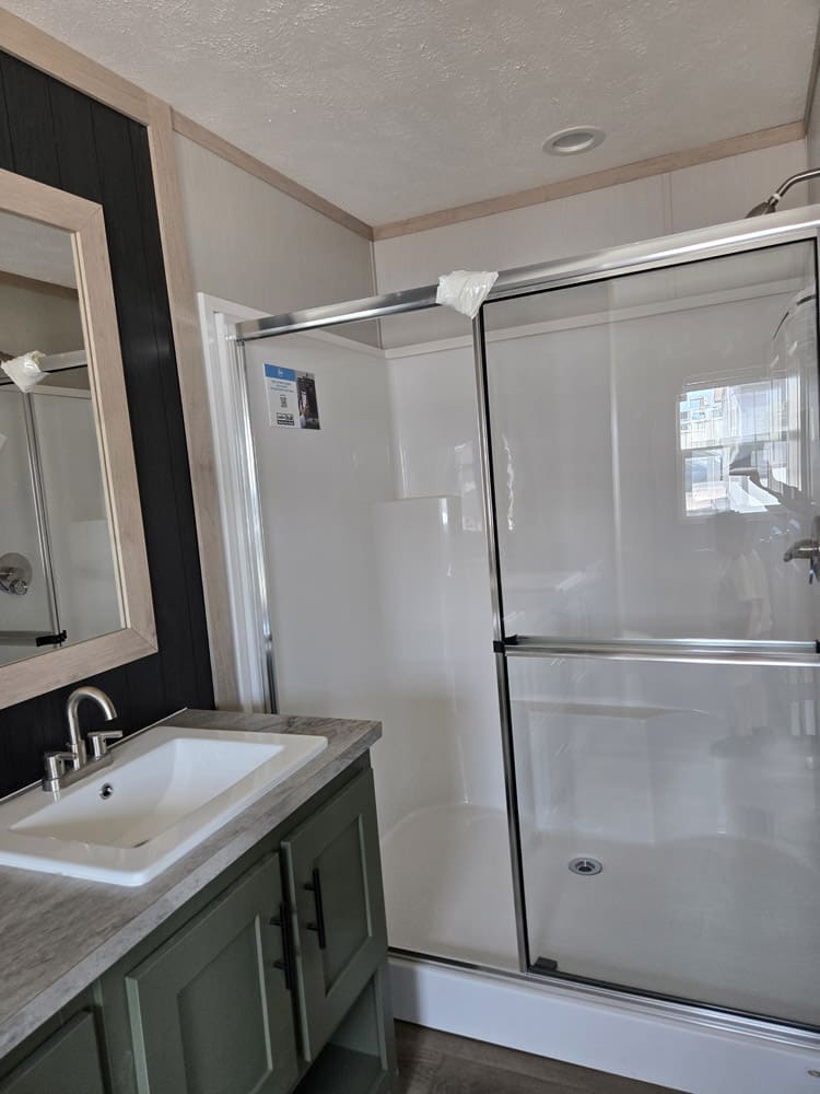 Glass shower enclosure beside the green vanity in the Clayton Epic Hudson 3-bedroom manufactured home