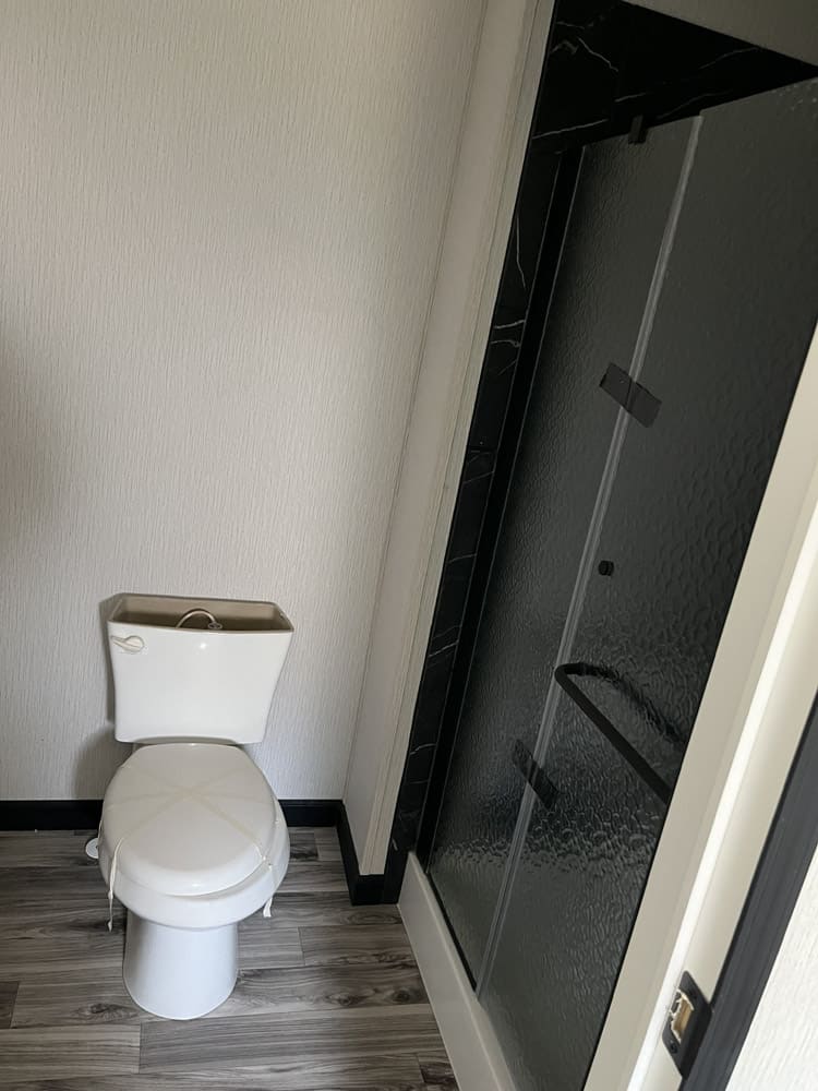 Toilet beside a glass shower enclosure in the Legacy C-3256-32B 3-bedroom manufactured home