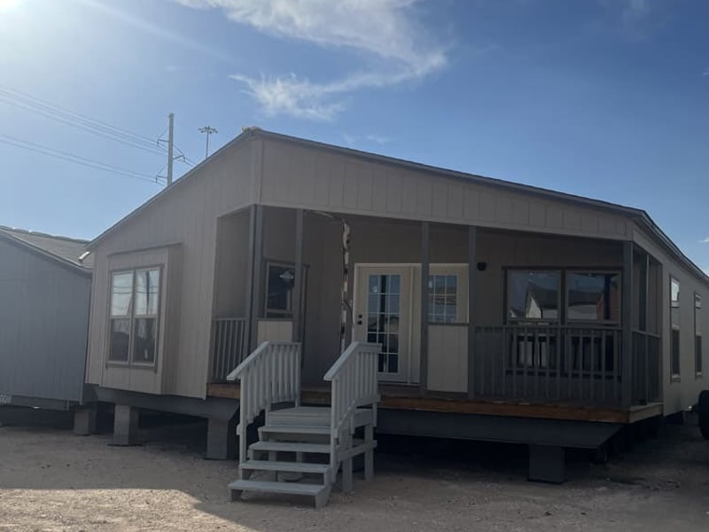 Covered front porch with gray siding and white steps in the Legacy FG-H-326432AD 32x64 home in El Paso