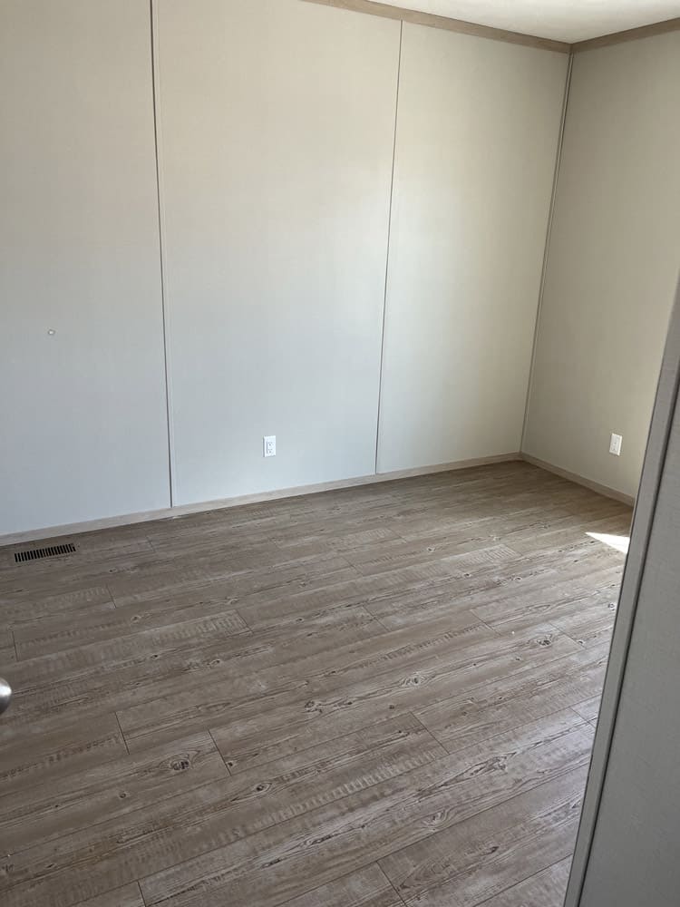 Bedroom with wood-look flooring in the Clayton Epic Mariner 16x80 home in El Paso