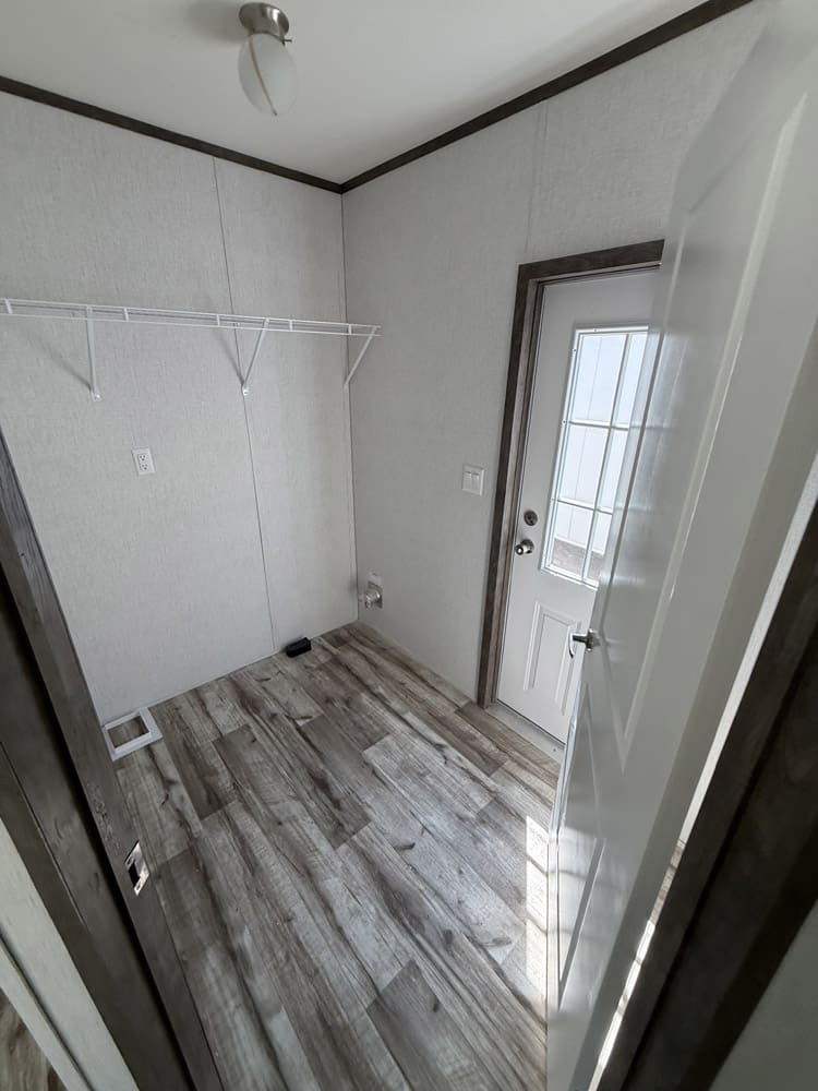 Laundry hookups, storage shelf and rear door in the Jessup Jackson 16x76 home in El Paso