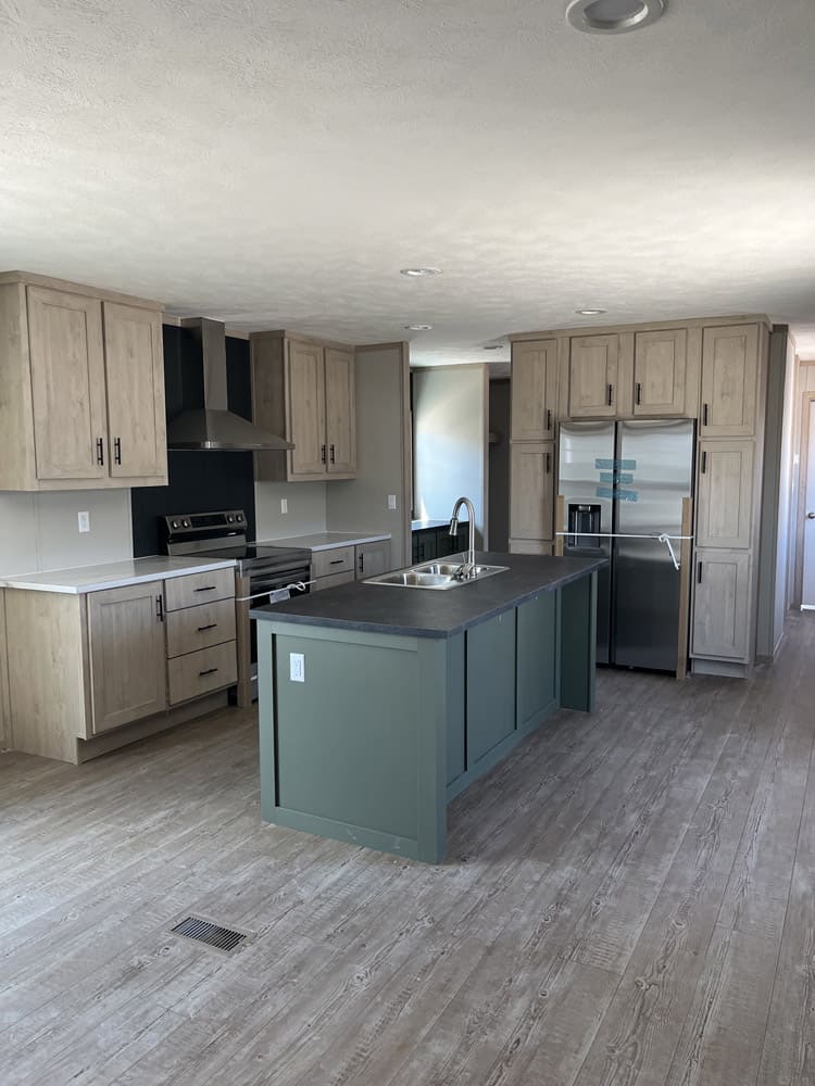 Green kitchen island and stainless appliances in the Clayton Epic Mariner home in El Paso