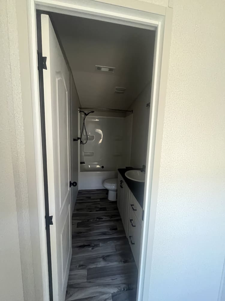 Bathroom doorway showing vanity and tub-shower combination in the Legacy FG-H-1664-22A home in El Paso