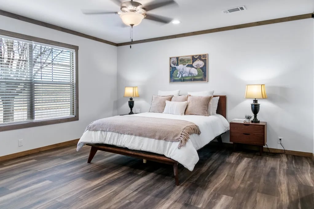 Primary bedroom with wide window and wood-look flooring in the Isabella Elite