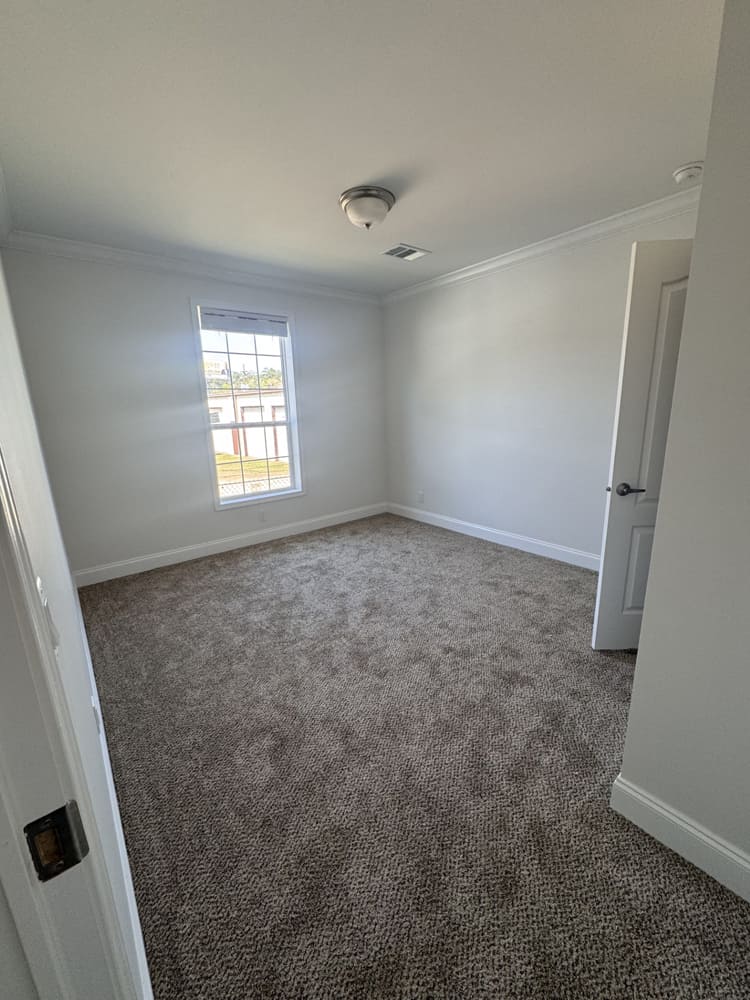 Carpeted bedroom with crown molding in The Shoreline 4-bed, 2-bath manufactured home near Conroe