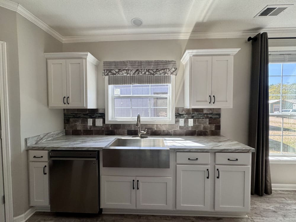 Farmhouse sink, dishwasher and bright cabinetry in The Ace 3 bedroom manufactured home