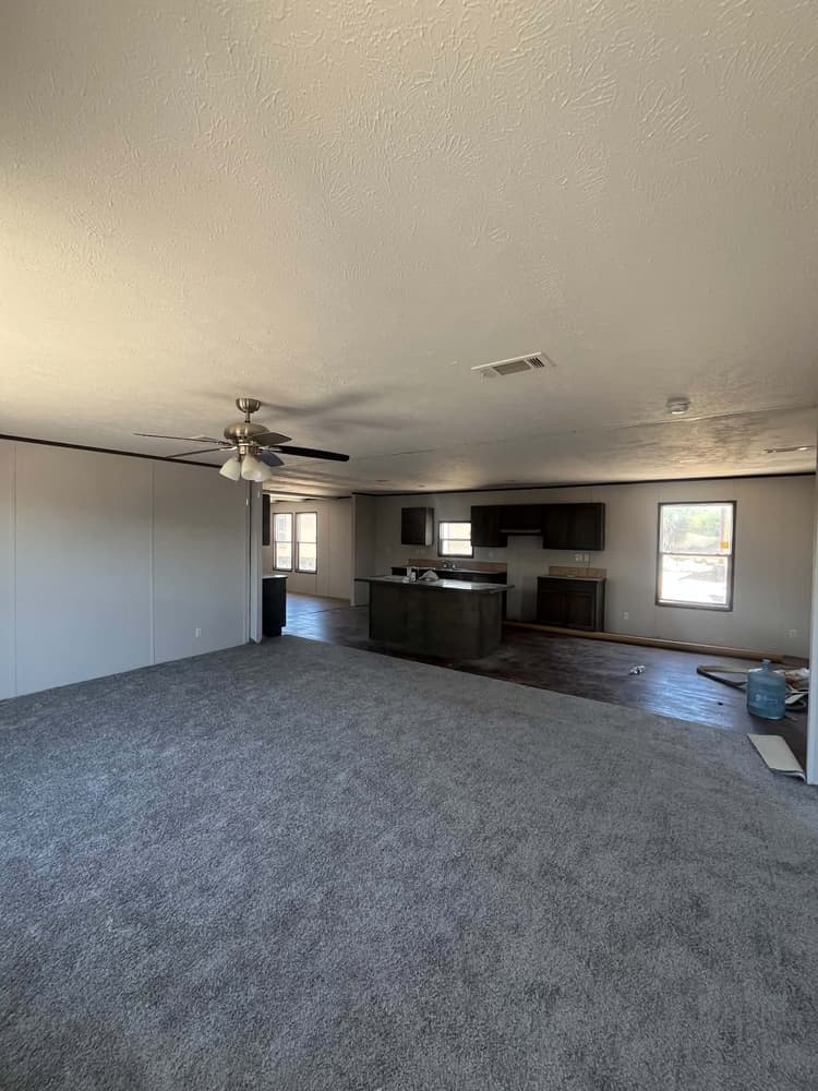 Carpeted living room opening to the kitchen in Cavco 28x72 home #3254 at New Start Homes in El Paso, TX