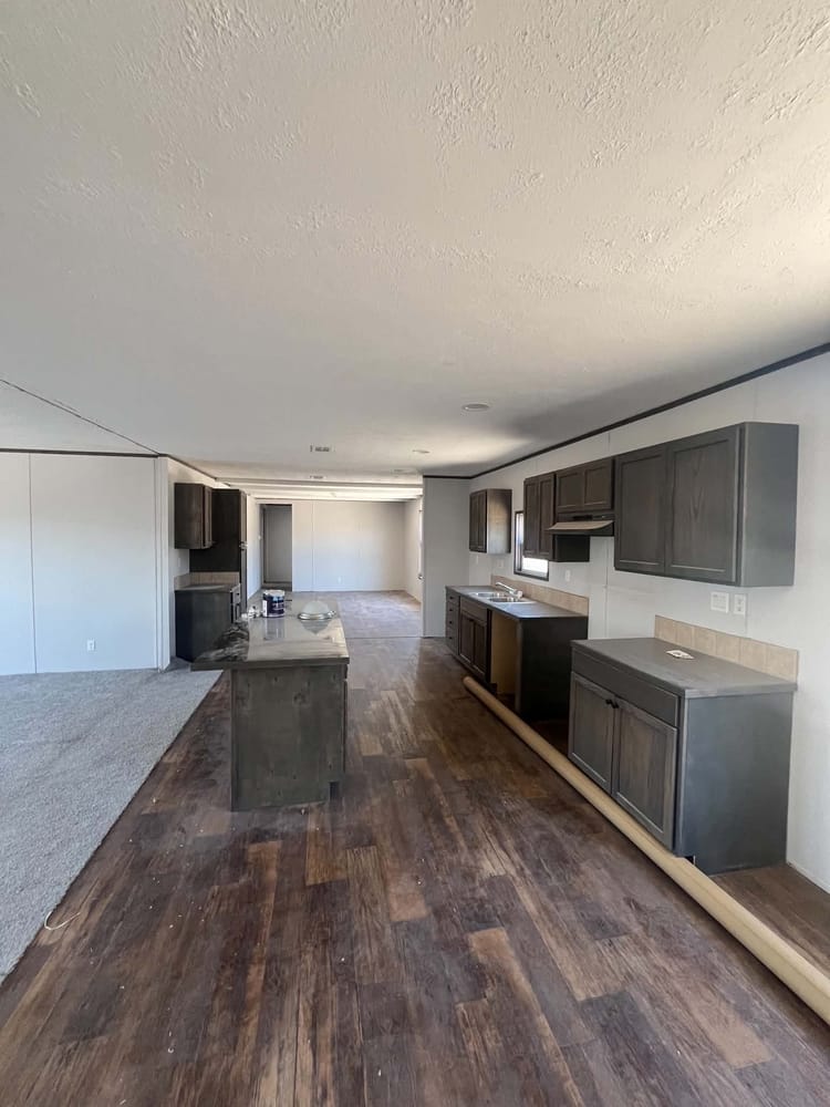 Kitchen island, dark cabinets and wood-look flooring in Cavco 28x72 home #3254 at New Start Homes in El Paso, TX