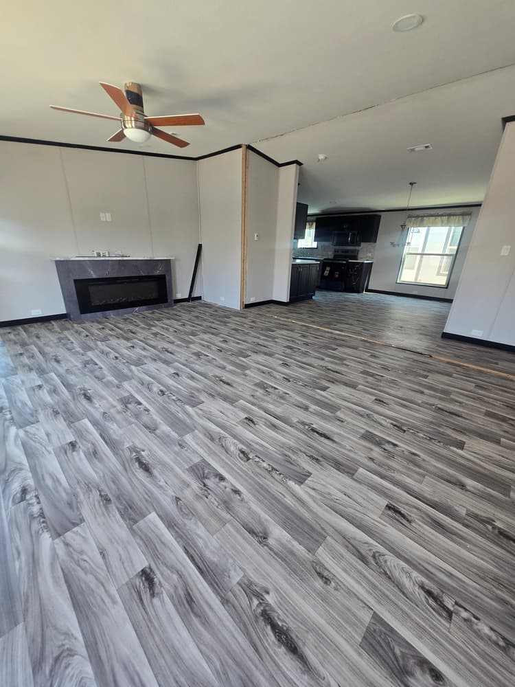Living room with fireplace opening to the kitchen in Legacy Housing H-3248-32A 32x48 home #5868 at New Start Homes in El Paso, TX