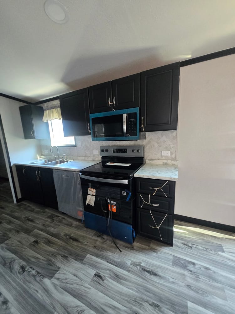 Kitchen range and microwave framed by dark cabinets in Legacy Housing H-3248-32A 32x48 home #5868 at New Start Homes in El Paso, TX