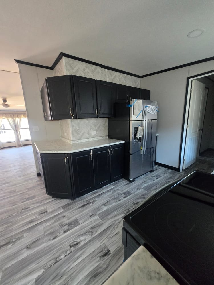 Refrigerator beside kitchen counter and cabinets in Legacy Housing H-3248-32A 32x48 home #5868 at New Start Homes in El Paso, TX