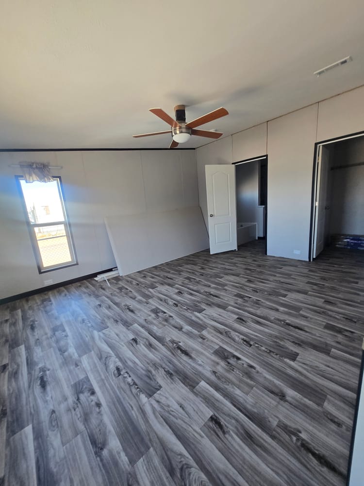 Bedroom with ceiling fan and wood-look flooring in Legacy Housing H-3248-32A 32x48 home #5868 at New Start Homes in El Paso, TX