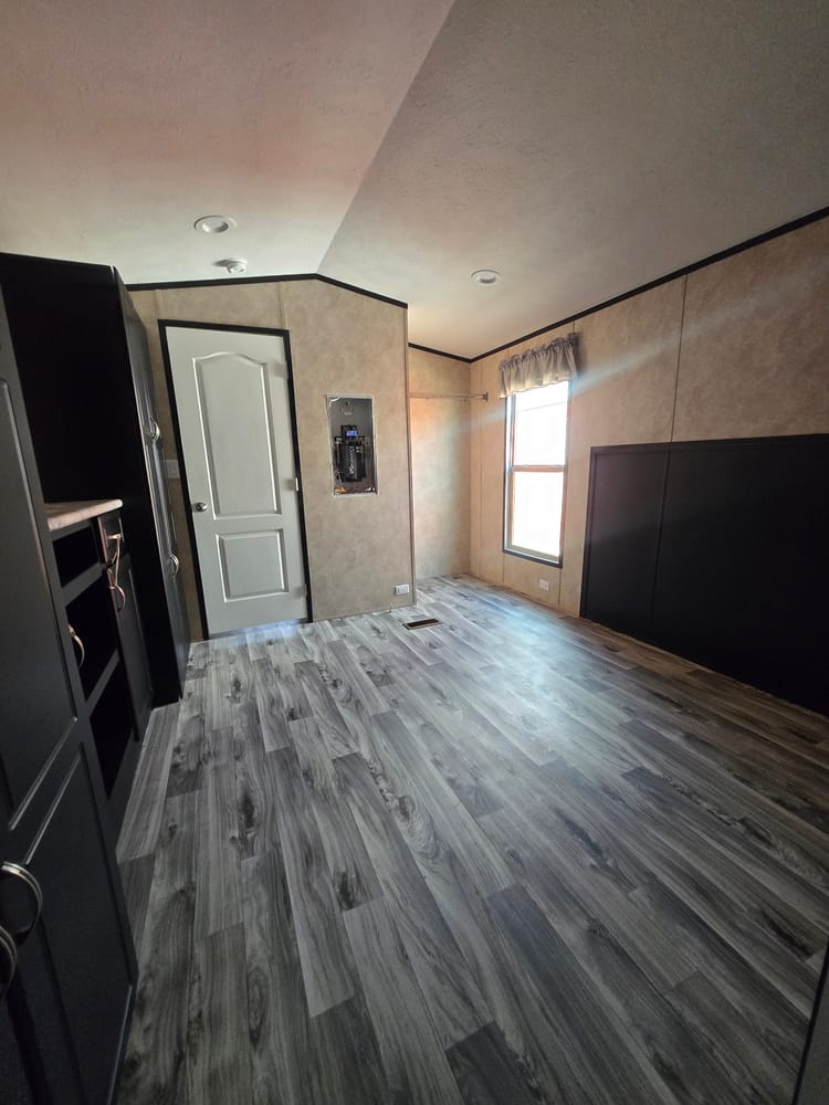 Living area with ceiling fan and front entry door in Legacy Housing S-1236-11FLA 12x36 home #5915 at New Start Homes in El Paso, TX