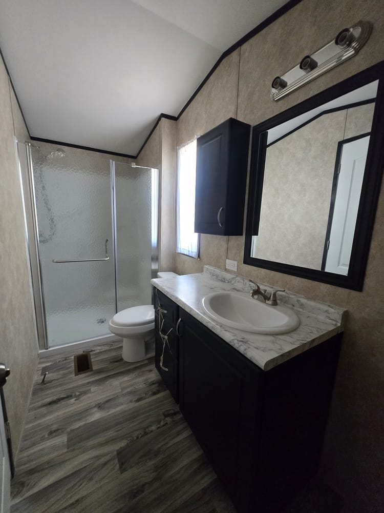 Bathroom vanity beside the walk-in shower in Legacy Housing S-1236-11FLA 12x36 home #5915 at New Start Homes in El Paso, TX