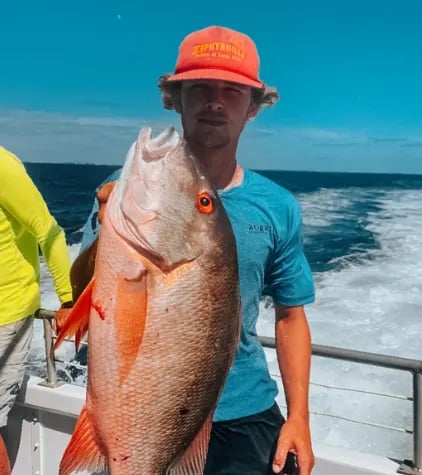 Angler holding a mutton snapper caught on the reef