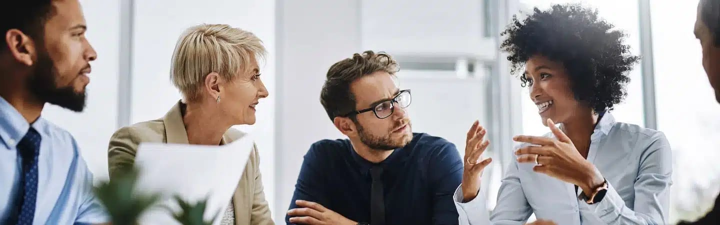 A diverse group of professionals engaged in a lively discussion in an office setting.