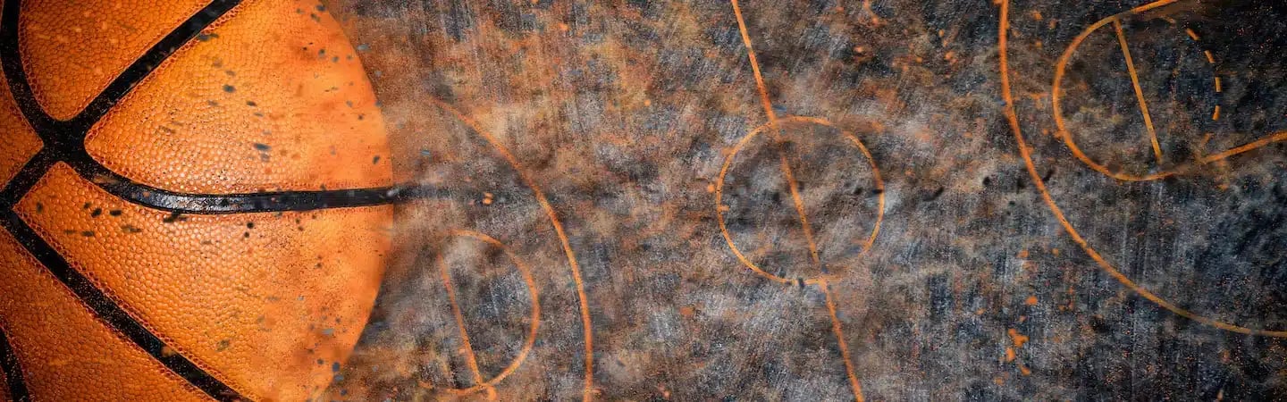 Close-up of a basketball on a worn court featuring multiple faded court markings.