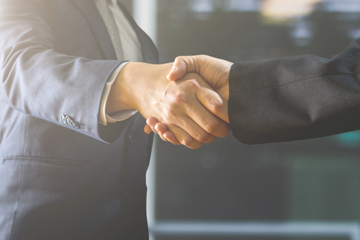 Two people in business suits shaking hands, symbolizing a successful agreement or partnership.