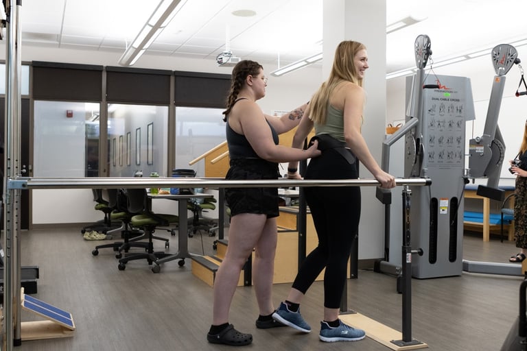 A physical therapist assists a woman using a walking rail in a rehabilitation center.