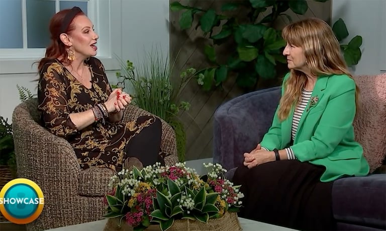 Two women sit facing each other in a studio setting, engaged in conversation about Stackable Degrees. One wears a black patterned dress, the other a green blazer. A floral centerpiece is on the table. “SHOWCASE” and Bryant & Stratton College appear in the corner.