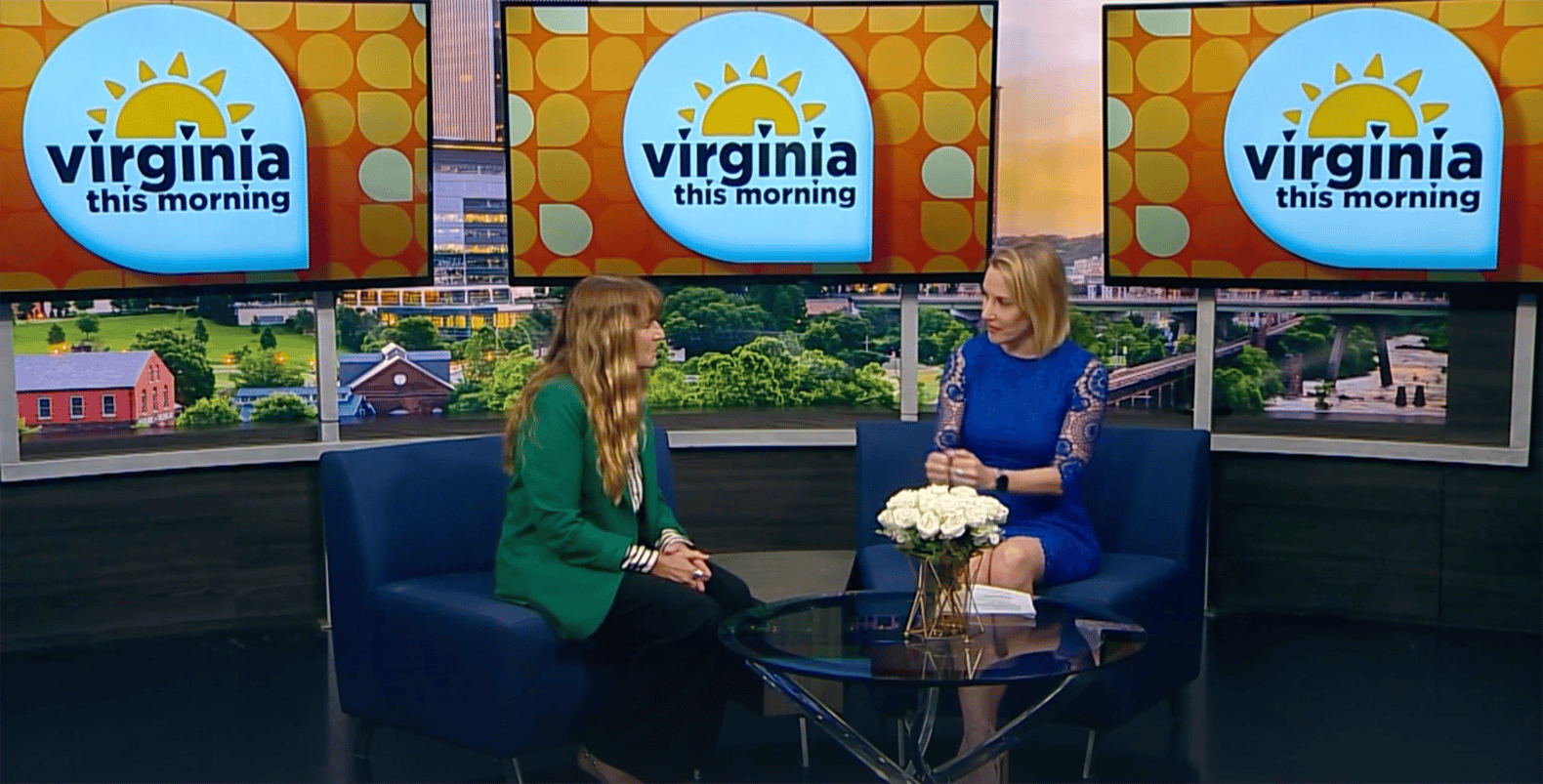 Two women sit on the "Virginia This Morning" TV studio set, discussing Bryant & Stratton College’s Rapid Registration for the Spring Semester. They’re seated in blue chairs with a small table and white flowers between them, three screens showing the show’s logo behind.