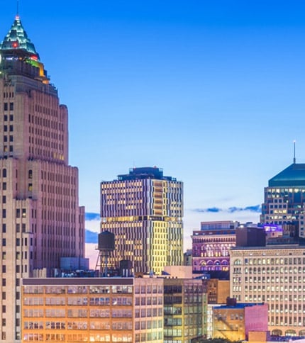 The illuminated Cleveland skyline at twilight, showcasing its mix of modern and historic architecture.