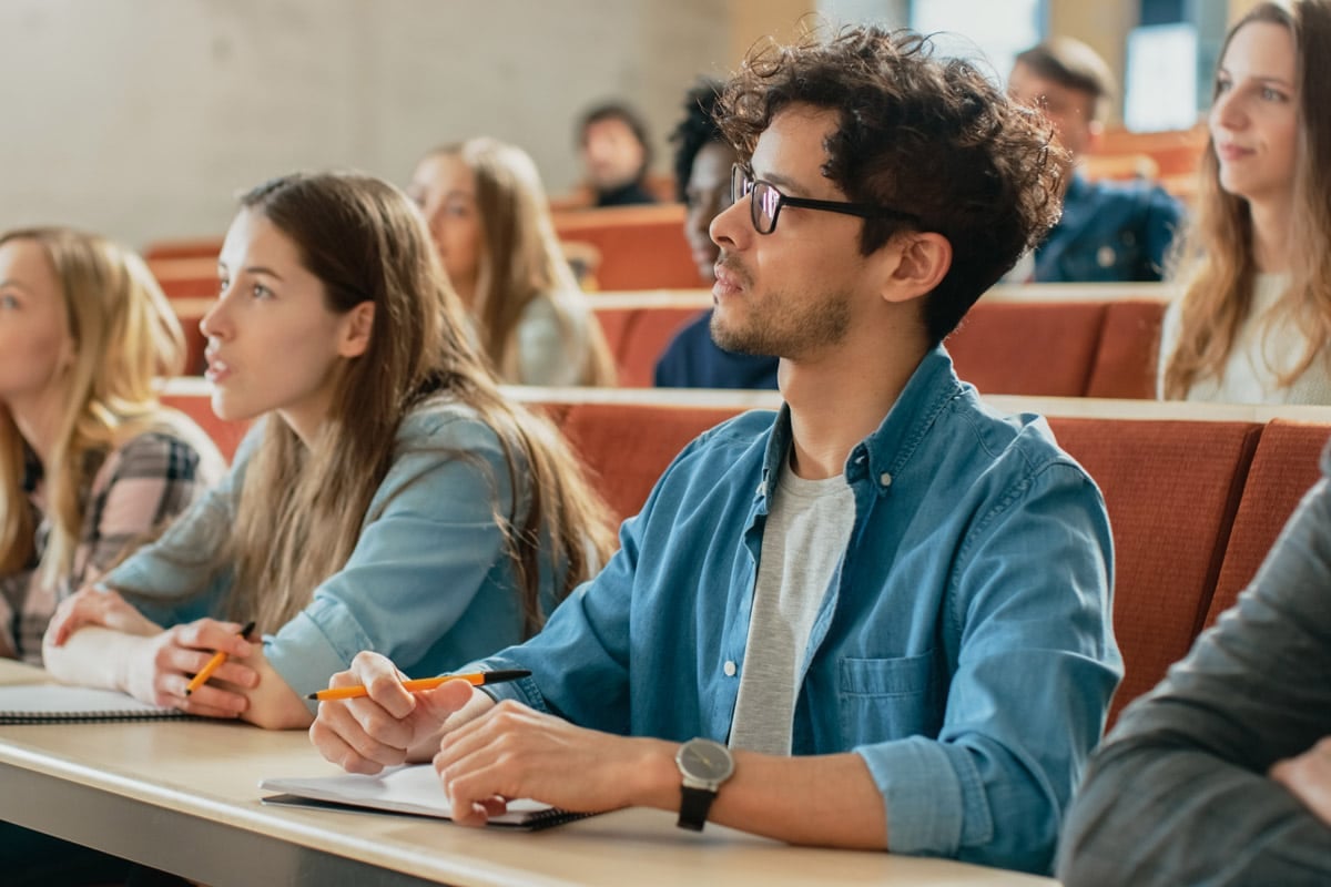 Students attentively listening and taking notes in a lecture hall.
