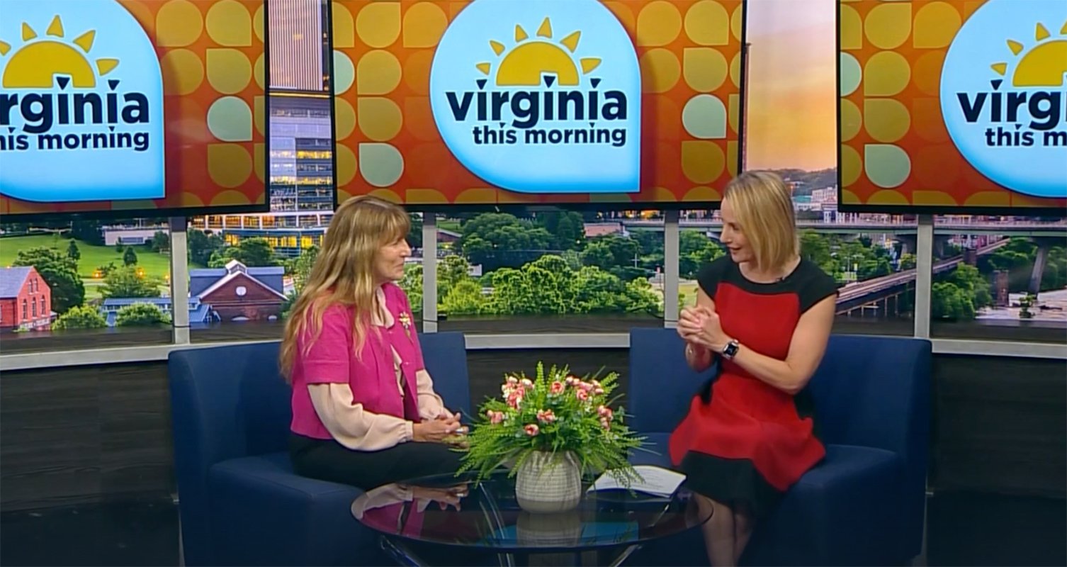 Two women sit and talk on the set of "Virginia This Morning," with show logos on screens behind them and a small table with a flower arrangement in front. Their discussion highlights opportunities in information technology careers and business careers, featuring insights from Bryant & Stratton College.