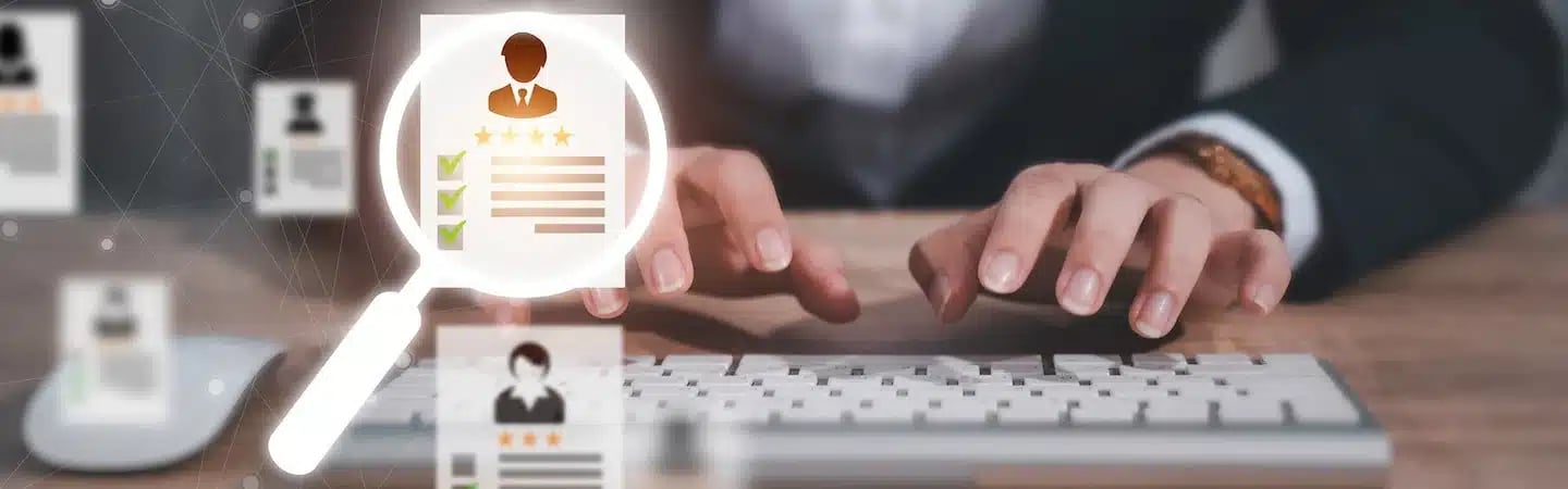 Person typing on a keyboard with a magnifying glass highlighting a profile with stars and checkmarks.