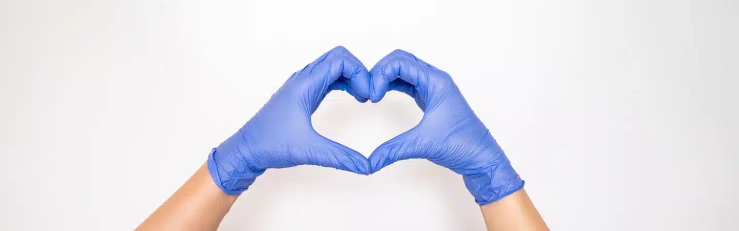 Hands wearing blue gloves forming a heart shape against a white background.