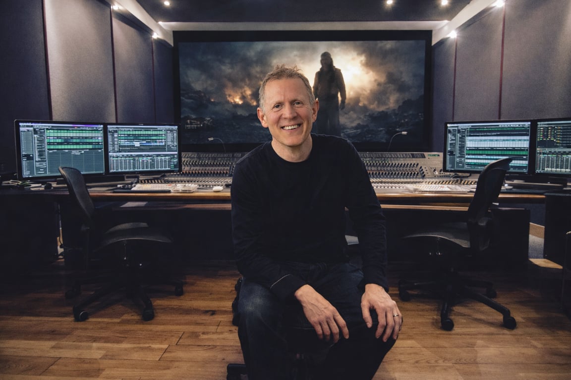 Giles Lamb in the studio, seated in front of the mixing desk and screens
