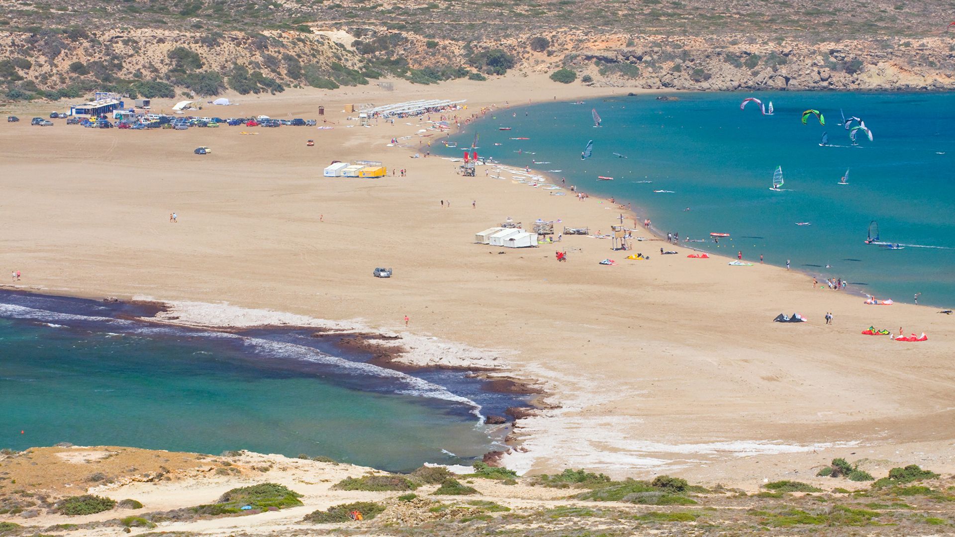 Prasonisi Beach Kitesurfing in Rhodos aerial shot from the sandy beach with water and kitesurfers on both sides of the land