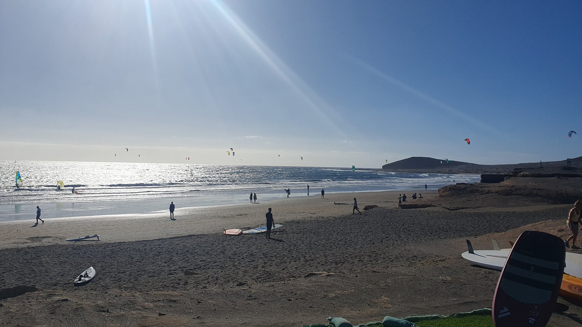 Playa El Medano Kiteboarding in Tenerife view into the sun with wind- and kitesurfers on gusty sea
